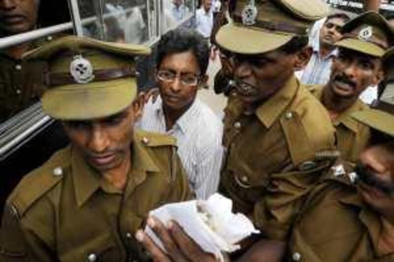 Sri Lankan prison officials escort Tamil journalist J. S. Tissainayagam (C) to a prison bus on August 31, 2009. Tissainayagam, 45, was sentenced by Sri Lanka's High Court to 20 years in prison for causing "racial hatred" and "supporting terrorism," a court official said. Tissainayagam, who contributed to the local Sunday Times and ran a website, Outreachsl.com, that focused on the island's Tamil population, was also found guilty of receiving money from the rebel group the Liberation Tigers of Tamil Eelam (LTTE) to fund his website. In custody since March 2008, Tissainayagam is the first Sri Lankan journalist to be convicted under the Prevention of Terrorism Act enacted in the early 1980s. His lawyers said they will appeal the conviction. AFP PHOTO/Ishara S.KODIKARA *** Local Caption ***  696763-01-08.jpg