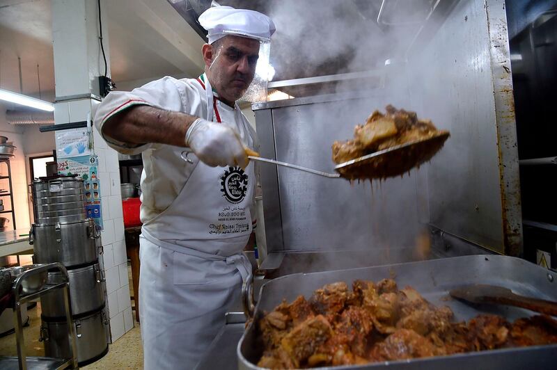 A volunteer of the "Nass el-Khir" association, wearing mask due to the COVID-19 coronavirus pandemic, prepares food for meals to be distributed among those in need during the Muslim holy fasting month of Ramadan, in Algeria's capital Algiers.   AFP