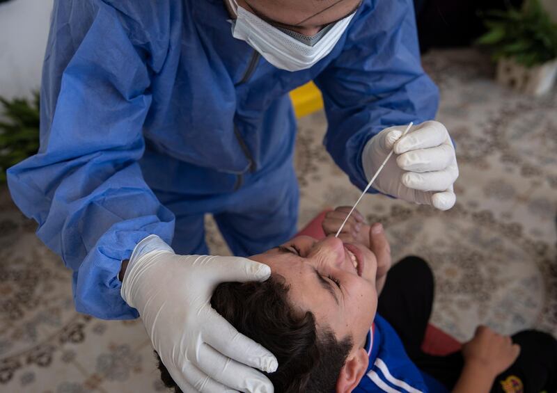 A Jordanian medic carries out swab tests for Covid-19 on a young boy, at Al Ramtha, about 70 kilometres north of Amman, near the Syrian border.  EPA
