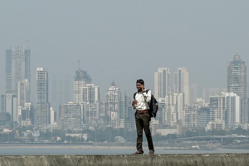 A man speaks on a mobile phone as he stands near the sea front overlooking the city skyline in Mumbai on February 18, 2020. / AFP / PUNIT PARANJPE
