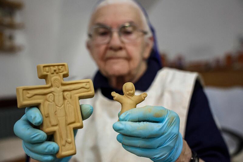 Sister Eliana, a French Catholic nun of the Little Sisters of Jesus, shows clay figurines of a crucifix and child to be sold during the Nativity season. AFP