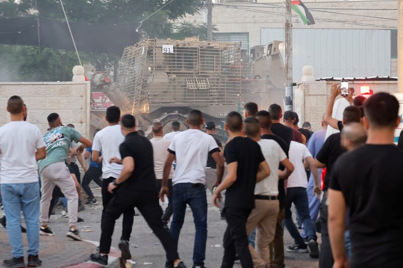 A crowd looks towards an armoured vehicle during the Israeli attack. Reuters