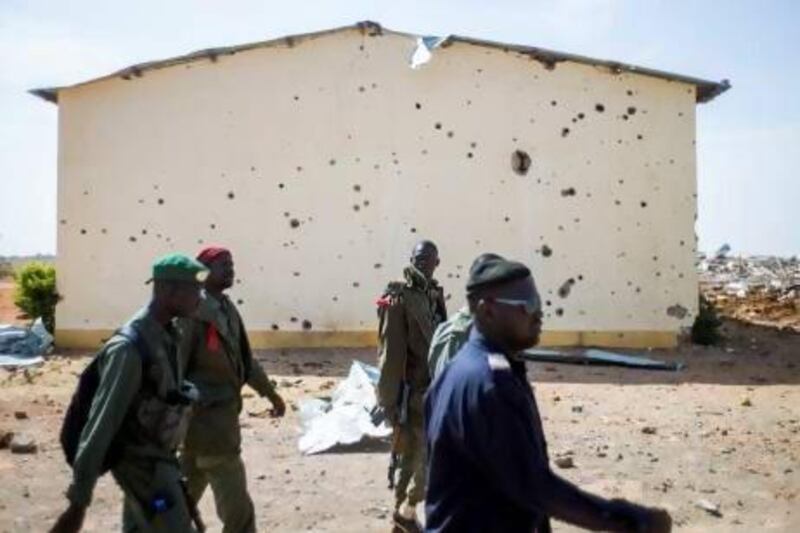 Malian soldiers walk past the bullet ridden wall of a house in a destroyed area of Konna on Saturday. Fred Dufour / AFP