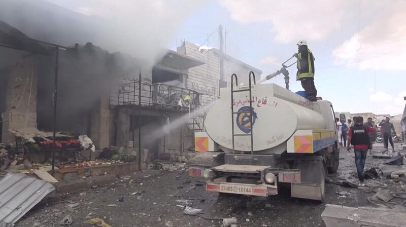 A member of a fire crew sprays water onto a damaged building in a market after an airstrike in this screen grab taken from a social media video said to be taken in Idlib, Syria on July 16, 2019. Picture taken July 16, 2019. White Helmets/social media via REUTERS THIS IMAGE HAS BEEN SUPPLIED BY A THIRD PARTY.