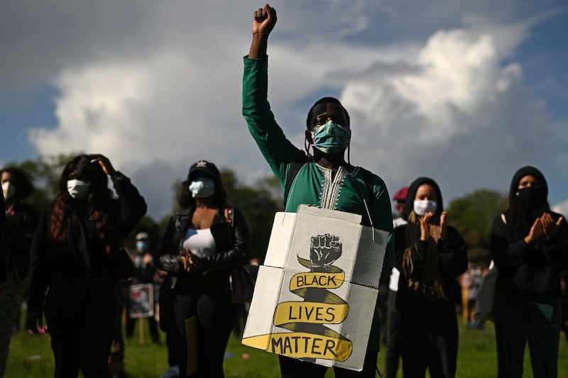 A protester wearing a protective face mask holds a placard at a gathering in support of the Black Lives Matter movement on Woodhouse Moor in Leeds in northern England, in the aftermath of the death of unarmed black man George Floyd in police custody in the US.   AFP