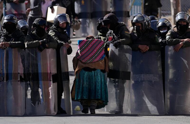 Police make way for an elderly woman to pass through while guarding the new coca leaf market during the third day of clashes in La Paz, Bolivia.  Anti-government coca farmers are protesting against a parallel coca leaf market in La Paz.  AP