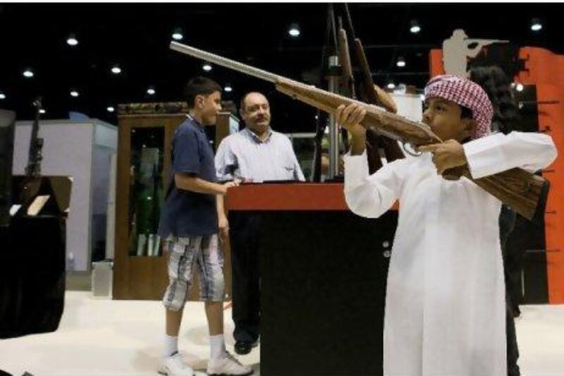 Ghanem Al Fandi Mazroui holds a rifle at his father’s company’s booth, MP3 International. Youngsters are allowed to handle the weapons but cannot buy them.