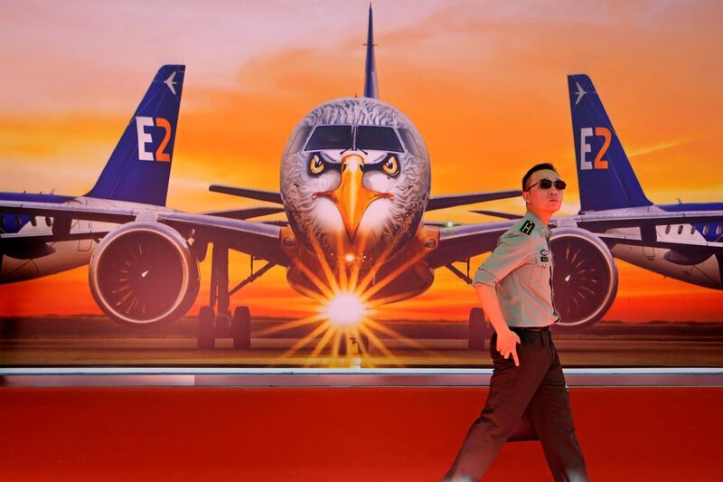 A visitor walks past a poster featuring the Embraer E190-E2 E190-E2 Commercial Jets during the 12th China International Aviation and Aerospace Exhibition, also known as Airshow China 2018, in Zhuhai city, south China's Guangdong province.(AP Photo