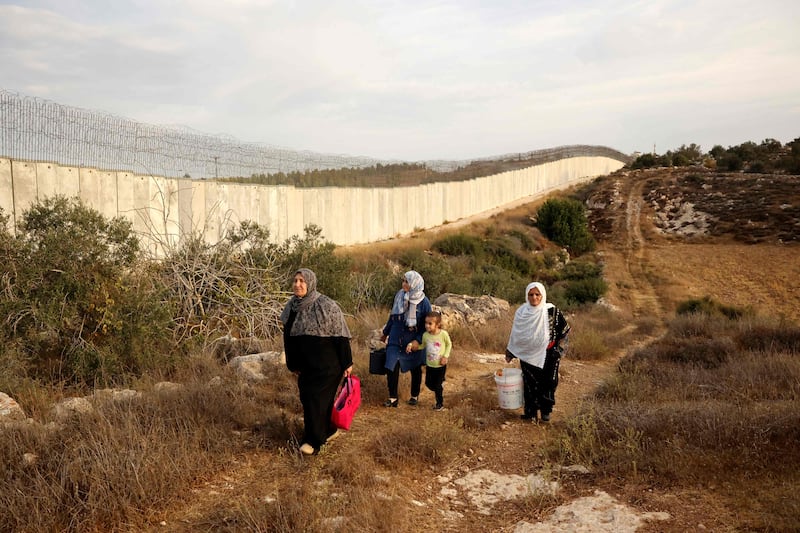 Palestinians walk alongside Israel's separation barrier after receiving special permission to harvest their olive trees, near Bait A'wa village, on the outskirts of the West Bank city of Hebron. AFP
