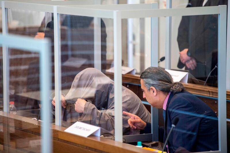 Syrian defendant Eyad al-Gharib (L) hides himself under his hood prior to a trial against two Syrian defendants accused of state-sponsored torture in Syria, on April 23, 2020 in Koblenz, western Germany. Two alleged former Syrian intelligence officers go on trial, accused of crimes against humanity in the first court case worldwide over state-sponsored torture by Bashar al-Assad's regime. Prime suspect Anwar Raslan, an alleged former colonel in Syrian state security, stands accused of carrying out crimes against humanity while in charge of the Al-Khatib detention centre in Damascus between April 29, 2011 and September 7, 2012. Fellow defendant Eyad al-Gharib, 43, is accused of being an accomplice to crimes against humanity, having helped to arrest protesters and deliver them to Al-Khatib in the autumn of 2011.
 / AFP / POOL / Thomas Lohnes
