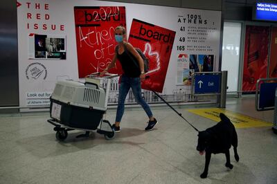 A woman wearing a face mask to prevent the spread of the new coronavirus, arrives with her dog from Amsterdam to the Eleftherios Venizelos International Airport in Athens, Monday, June 15, 2020. Greece is officially open to tourists as of Monday, with the first international flights expected into Athens and the northern city of Thessaloniki where passengers will not face compulsory COVID-19 tests. Seasonal hotels and museums are also opening across the country. (AP Photo/Thanassis Stavrakis)