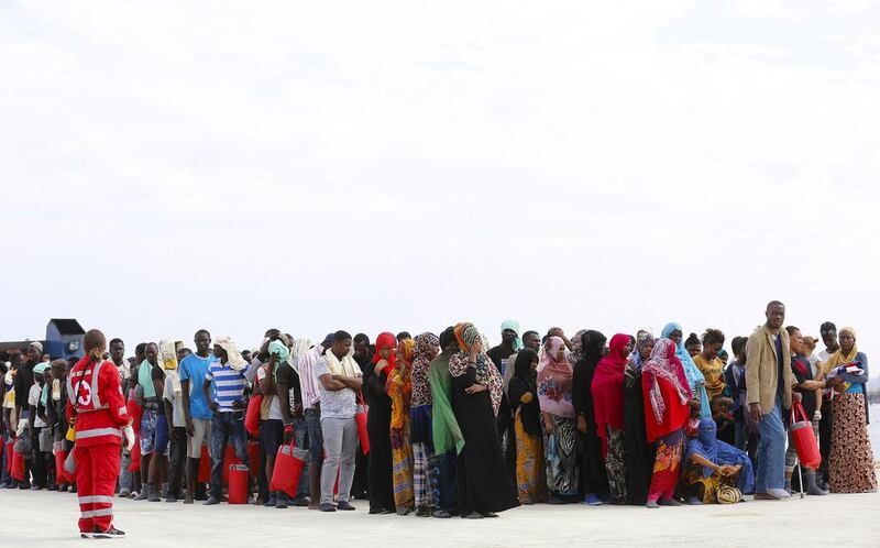 Migrants wait on the dock after disembarking from a Medecins Sans Frontieres ship carrying 320 migrants in the Sicilian harbour of Augusta, Italy, on August 25, 2015. Antonio Parrinello / Reuters