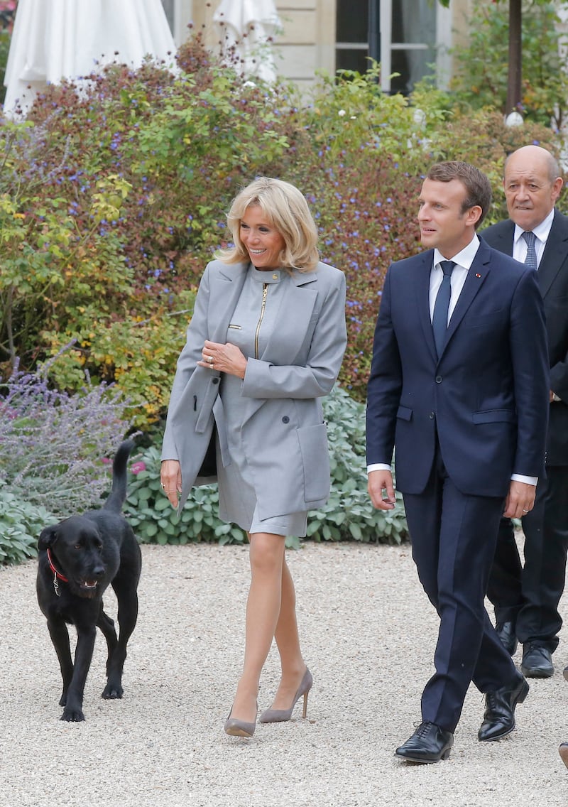 Brigitte, wearing a grey Louis Vuitton dress and coordinated coat, Emmanuel Macron and their dog Nemo, on September 27, 2017. AFP