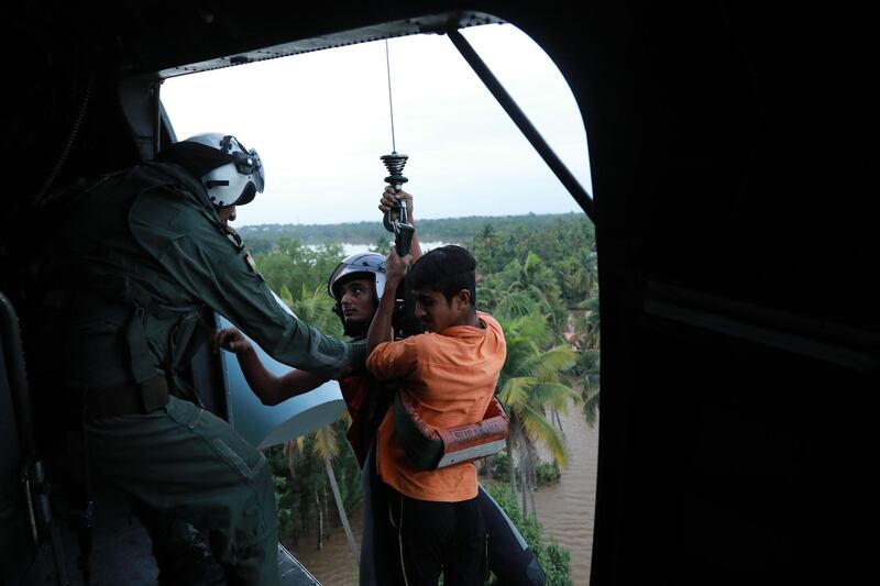 Indian People are airlifted by Navy personnel during a rescue operation at a flooded area in Paravoor near Kochi, in the Indian state of Kerala on August 18, 2018. - Rescuers in helicopters and boats fought through renewed torrential rain on August 18 to reach stranded villages in India's Kerala state as the toll from the worst monsoon floods in a century rose above 320 dead. (Photo by - / AFP)