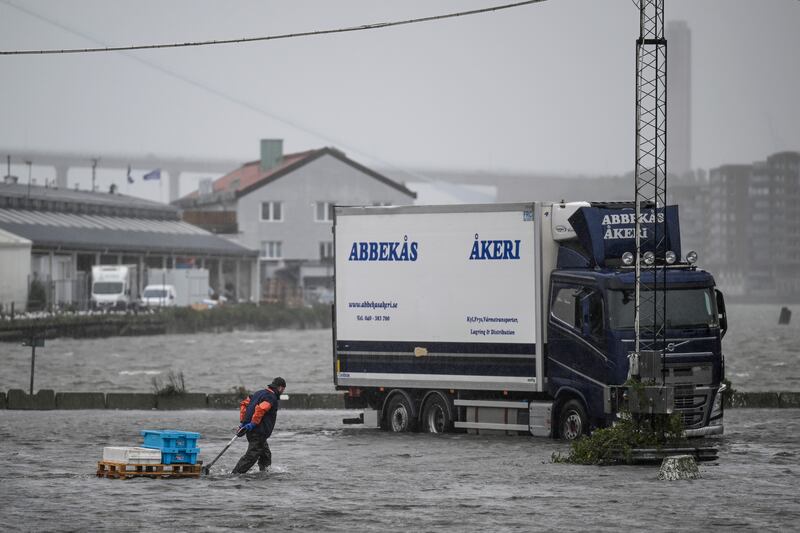 A man wades through the flooded fishing port in Gothenburg, Sweden, after the Gota river burst its banks. AP
