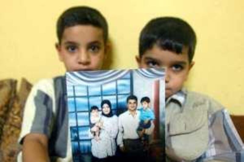 Hassan (L) sits with his younger brother Ali as they show off a family photo at their home in Basra, 500 kms south of Baghdad 20 July 2005. British Corporal Donald Payne, 34, faces manslaughter charges over the death of the father of the boys, Baha Mousa, a 26-year-old hotel receptionist in Basra. Mousa was taken into custody by soldiers from the Queen's Lancashire Regiment in September 2003 and died in custody several days later. Lance Corporal Wayne Crowcroft, 21, and Private Darren Fallon, 22, both from the same regiment, are also charged with war crimes.  AFP PHOTO/ESSAM AL-SUDANI