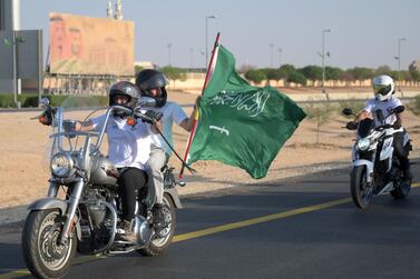 Saudi and exapt riders of the Hawks Riyadh MC club wave a national flag as they ride their motorcycles around the capital Ryad on September 23, 2020, during a parade to mark the Saudi national day. / AFP / FAYEZ NURELDINE