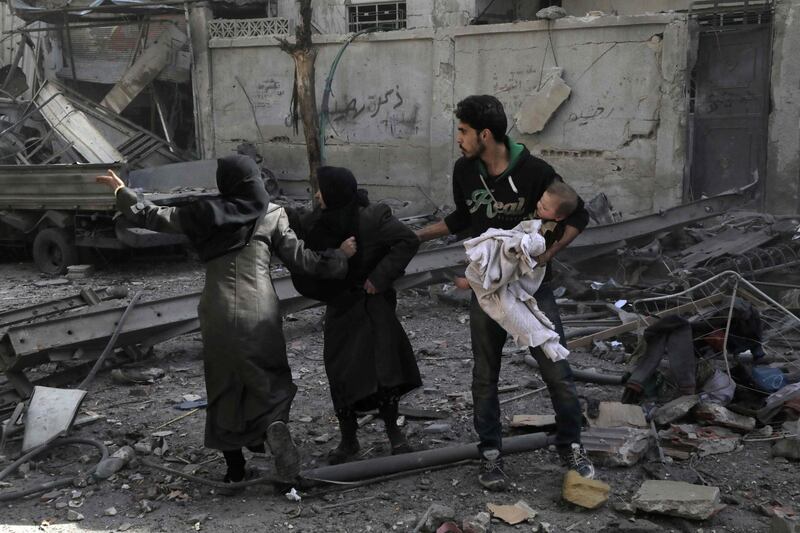 TOPSHOT - Syrians run for cover following Syrian government air strikes on the Eastern Ghouta rebel-held enclave of Douma, on the outskirts of the capital Damascus on March 20, 2018.
Syrian regime and allied forces battled to suppress the last pockets of resistance in and around Damascus while the beleaguered Kurds in the north braced for further Turkish advances. Assad has in recent months brought swathes of territory back under his control thanks to heavy Russian involvement, as well as support from other forces such as the Iran-backed Lebanese Hezbollah militia. Eastern Ghouta's main town of Douma remains under rebel control but even as a trickle of emergency medical evacuations was scheduled to continue, the regime continued to pound the enclave. / AFP PHOTO / HAMZA AL-AJWEH