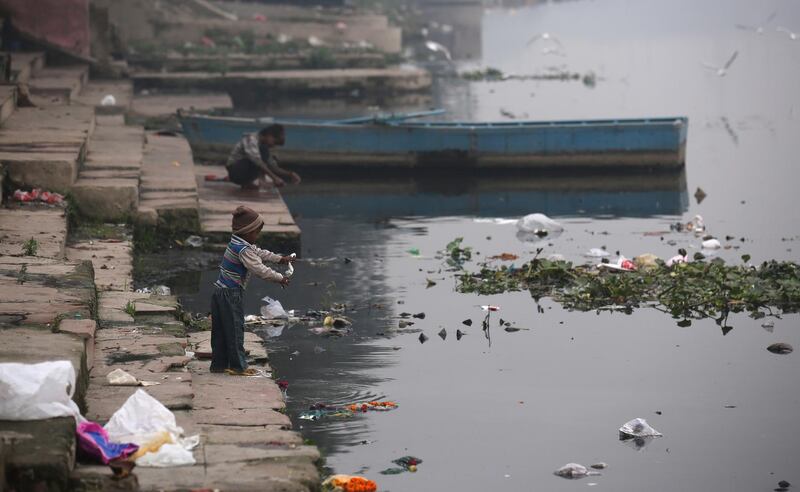 epaselect epa06367998 An Indian child throws prayer materials into the polluted Yamuna river in New Delhi, India, 05 December 2017. About 57 million people depend on Yamuna waters for washing and drinking, despite the river being heavily polluted and laden with sewage.  EPA/RAJAT GUPTA