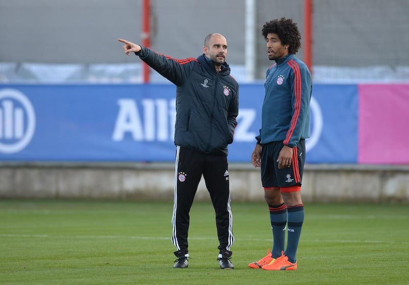 Bayern Munich manager Pep Guardiola, left, speaks to defender Dante on Monday during the final team training before they meet Arsenal in a Uefa Champions League last-16 second-leg match Tuesday night in Munich. Christof Stache / AFP

