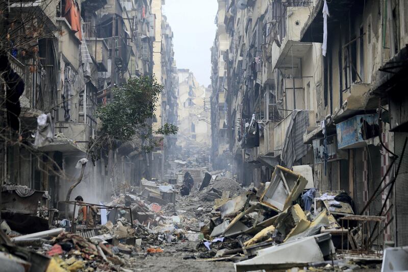 Residents walk through the destruction of the once rebel-held Salaheddine neighborhood in eastern Aleppo, Syria, Friday, Jan. 20, 2017. Last month, government forces captured all parts of eastern Aleppo, brining Syria's largest city to full control of Syrian authorities for the first time since July 2012. (AP Photo/Hassan Ammar)