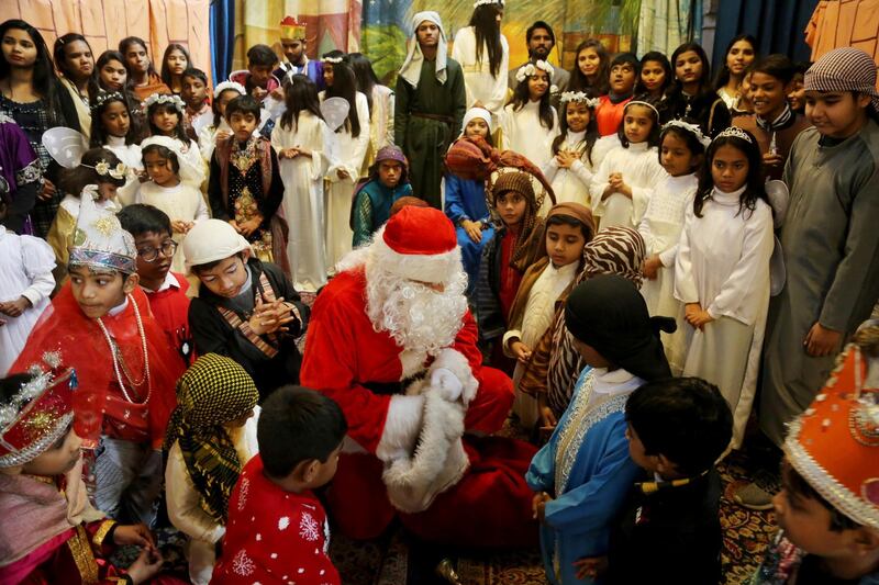 A man dressed as Santa Claus distributes candy and other gifts to children during a Christmas celebration at the Church of the Resurrection, in Lahore, Pakistan, on Sunday, Dec. 15, 2019. (AP Photo/K.M.Chaudary)