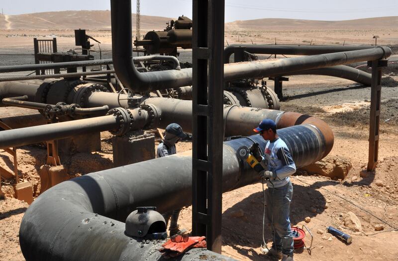 A picture taken on July 9, 2017 shows workers at Syria's Arak gas field, 35 kilometres (20 miles) northeast of the ancient city of Palmyra, in the central province of Homs, a few weeks after it was retaken by government forces from the hands of jihadists of the Islamic State group. 
Arak, like much of the surrounding desert region of Badiya, had been in the hands of the jihadists since 2015. The army is pressing an offensive to recapture the vast region, which stretches from central Syria to the borders with Iraq and Jordan.
 / AFP PHOTO / STRINGER