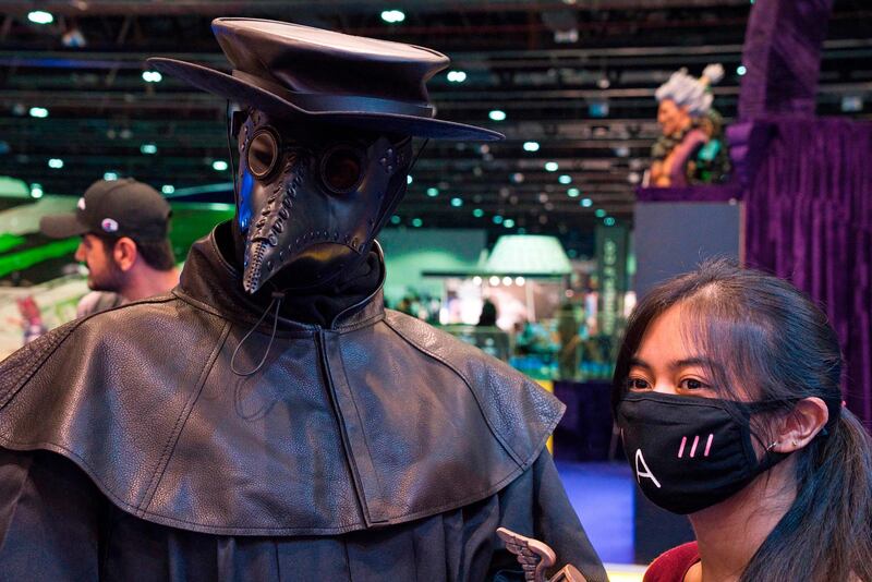 A cosplayer wearing the long, black nose of a plague doctor poses with a woman in a face mask for a photo. AP Photo