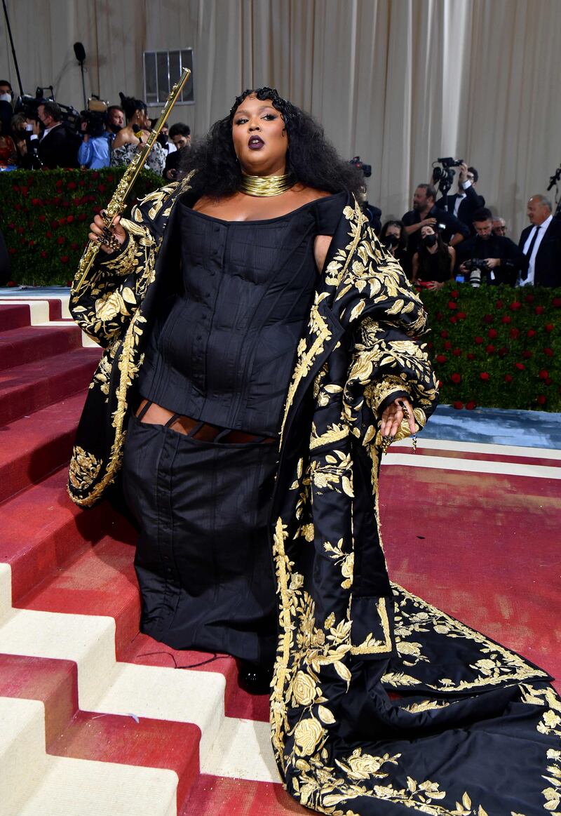 Lizzo in a trailing gold-embroidered coat, black gown and gold choker arrives for the 2022 Met Gala in New York on May 2, 2022. AFP