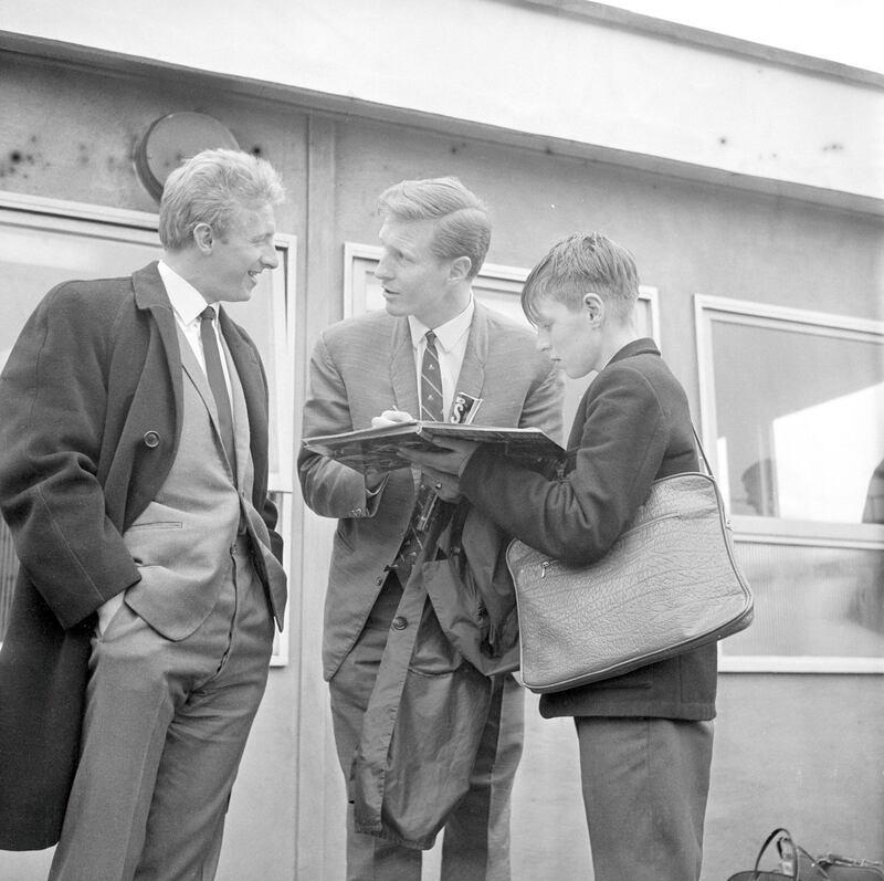 8th April 1965:  Scottish footballers Billy McNeill (centre) and Denis Law signing autographs for a young fan after their arrival at Heathrow Airport for Scotlands game against England. Law made his name with Manchester United before becoming a hero on the other side of Manchester when he backheeled United into the second division while playing for their arch- rivals Manchester City. McNeill was captain of the famous Celtic team known as the Lisbon Lions, which beat Inter Milan in 1967 becoming the first British team to win the European Cup.  (Photo by Roger Jackson/Central Press/Getty Images)