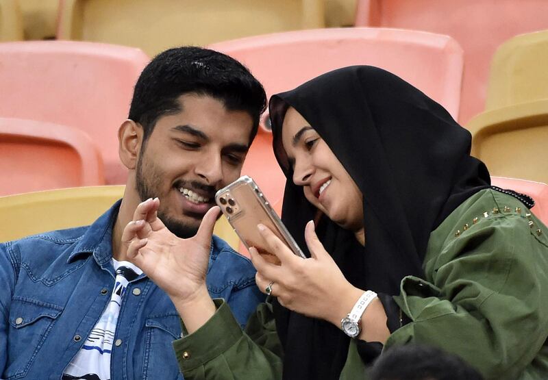 A picture taken on January 12, 2020 shows a Saudi couple attending a football match at King Abdullah Sport City Stadium in Jeddah. In Saudi Arabia's rigid past, religious police once swooped down on rose sellers and anyone peddling red paraphernalia around Valentine's Day, but now a more open -- albeit risky -- dating culture is taking root. Pursuing relationships outside of marriage in the conservative Islamic kingdom once amounted to a death wish, and would-be Romeos resorted to pressing phone numbers up against their car window in hope of making contact with women. / AFP / FAYEZ NURELDINE
