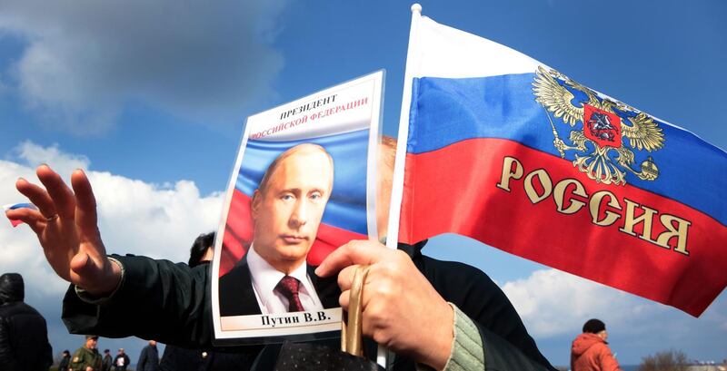 (FILES) In this file photo taken on March 18, 2017, A person waves a Russian national flag and a portrait of Russian President Vladimir Putin as they celebrate the third anniversary of the annexation of the Crimea by the Russian Federation, in Sevastopol. The US government said on July 25, 2018, it will not accept Russia's annexation of the Crimea region from Ukraine, a declaration apparently aimed at highlighting President Donald Trump's intent to hold the Kremlin accountable for its aggression. / AFP / Max Vetrov
