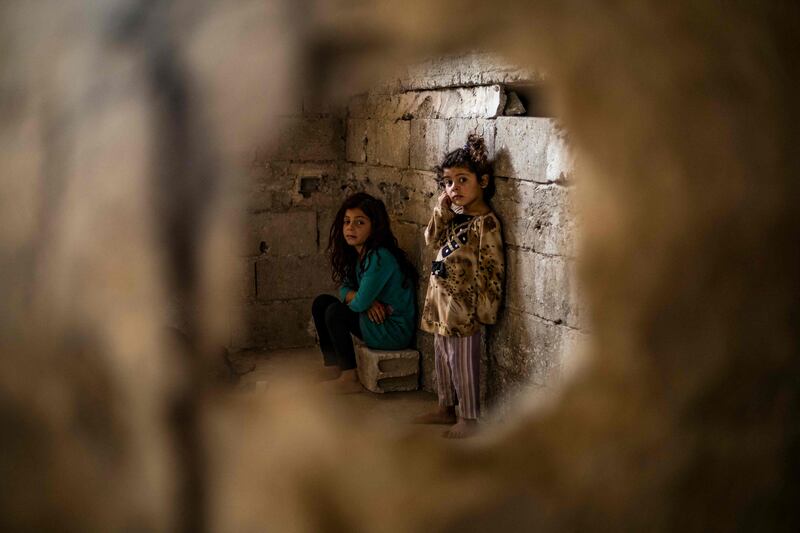 Syrian girls, displaced with their family from Deir Ezzor, look at the camera inside the damaged building where they are living in Syria's northern city of Raqqa.