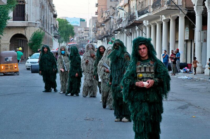 Anti-government protesters wear camouflage sniper uniforms during anti-government protests in Baghdad. AP Photo