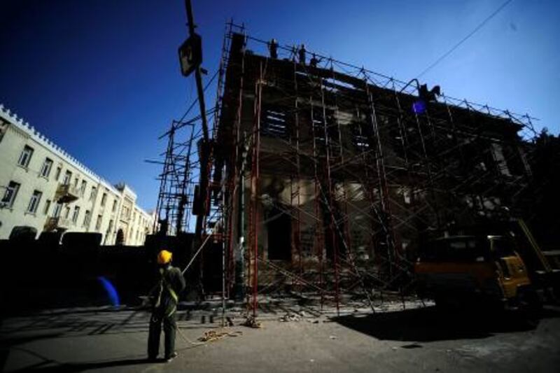 Egyptian construction workers restore the burnt Scientific Institute in central Cairo, on December  27, 2011 after it was set ablaze during clashes on December 17. Damaged manuscripts and books were transferred to Egyptís National Library and Archives for restoration, while architects started repairing the burnt building. The Scientific Institute was built in 1798 during the French campaign to invade Egypt led by Napoleon Bonaparte.  AFP PHOTO/Filippo MONTEFORTE