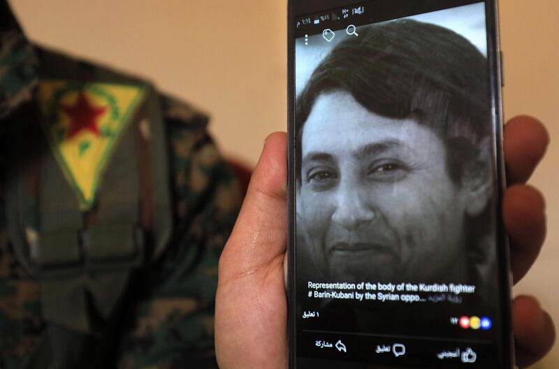 A picture taken on February 2, 2018 in the town of Afrin shows, Amed Kendal, a military commander of the Syrian Kurdish Women's Protection Units (YPJ), displaying a picture of late 23-year-old YPJ fighter Barin Kobani, after the YPJ and the Syrian Observatory for Human Rights accused Turkish-backed Syrian rebels of filming the mutilation of her dead body. / AFP PHOTO / Delil souleiman