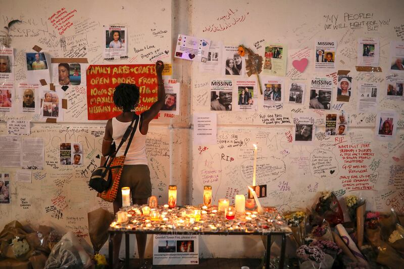 A woman writes on a wall covered with tributes to and pictures of the victims of the Grenfell apartment tower fire in North Kensington, London. Marko Djurica / Reuters