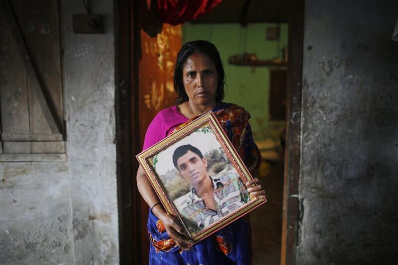 Fatema holds a picture of her son Nurul Karim as she poses for a photograph in front of her slum house in Savar. Fatema lost her son Nurul Karim and her daughter Arifa, who were working on the fifth floor of Rana Plaza when it collapsed on April 24, 2013. Andrew Biraj / Reuters