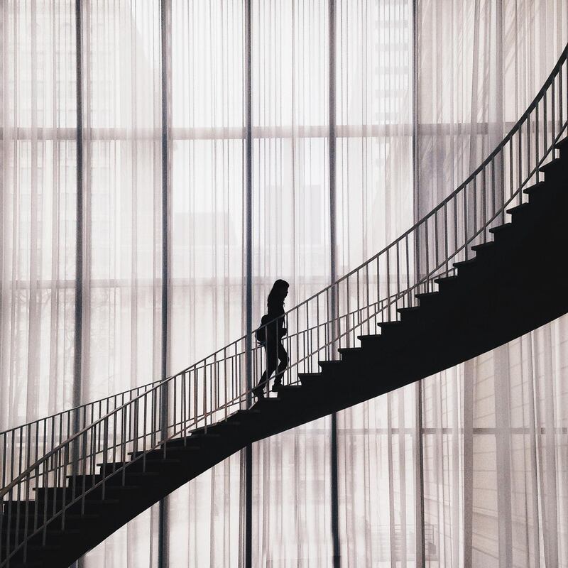 Silhouette Woman Walking On Staircase In Building. Getty Images
