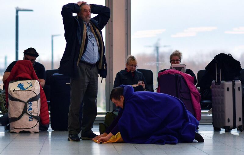 A passenger rolls away a sleeping aid as she sits with their luggage in the South Terminal building at London Gatwick Airport, south of London, on December 21, 2018, as flights started to resume following the closing of the airfield due to a drones flying. British police were Friday considering shooting down the drone that has grounded flights and caused chaos at London's Gatwick Airport, with passengers set to face a third day of disruption. Police said it was a "tactical option" after more than 50 sightings of the device near the airfield since Wednesday night when the runway was first closed. 
 / AFP / Ben STANSALL
