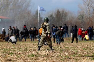 A Turkish soldier walks past migrants clashing with Greek riot police on the Turkey-Greece border in the Edirne region on March 7, 2020. AP Photo