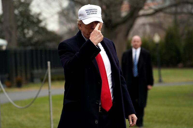 U.S. President Donald Trump points to his hat for the press on South Lawn as he returns to the White House in Washington, U.S., after visiting the FBI Academy in Quantico, Virginia, U.S. December 15, 2017. REUTERS/Yuri Gripas