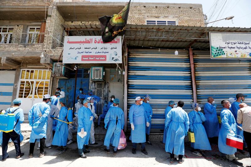 Healthcare workers gather in a street during testing for the coronavirus disease  in Sadr city, district of Baghdad, Iraq. REUTERS