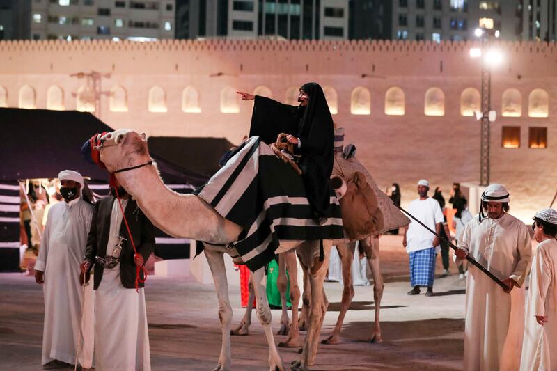 Actors walk around in traditional dress on camels.