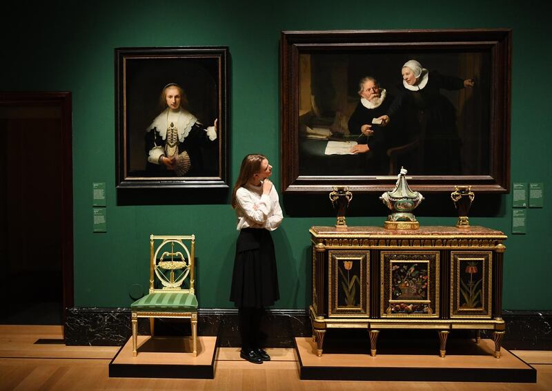 epa07995205 A Royal Collection employee poses for photographers next to a painting entitled 'The Shipbuilder and his Wife' (R) by Dutch artist Rembrandt van Rijn during a photocall of the Royal Collection's 'George IV: Art & Spectacle' exhibition in the Queen's Gallery at Buckingham Palace in London, Britain, 14 November 2019. The exhitibiton will open to the public from 15 November 2019 until 03 May 2020.  EPA/FACUNDO ARRIZABALAGA