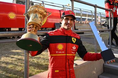 Ferrari's Spanish driver Carlos Sainz Jr poses with the winner's trophies after the Formula One British Grand Prix at the Silverstone motor racing circuit in Silverstone, central England on July 3, 2022.  (Photo by JUSTIN TALLIS  /  AFP)