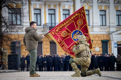 Ukrainian President Volodymyr Zelenskyy holds the flag of a military unit as an officer kisses it in Kyiv, Ukraine last month. AP Photo