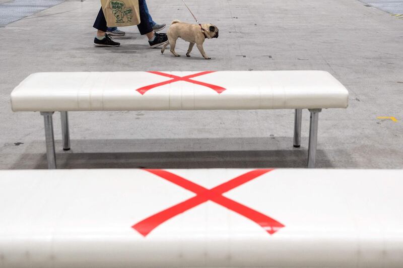 A visitor walks with a dog past signs for social distancing on benches during the Interpets fair for pet products in Tokyo, Japan. AFP