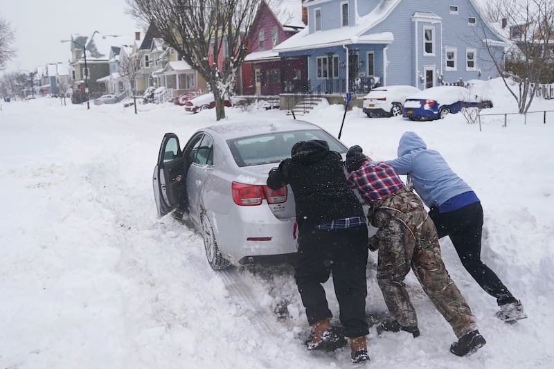 Neighbours push a motorist stuck in the snow in the Buffalo region. AP