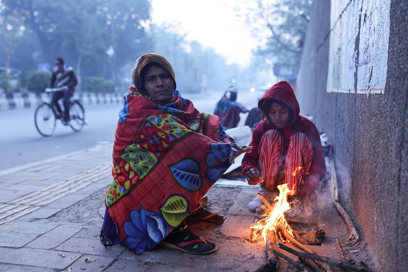 A woman and her daughter warm themselves by a fire. Reuters